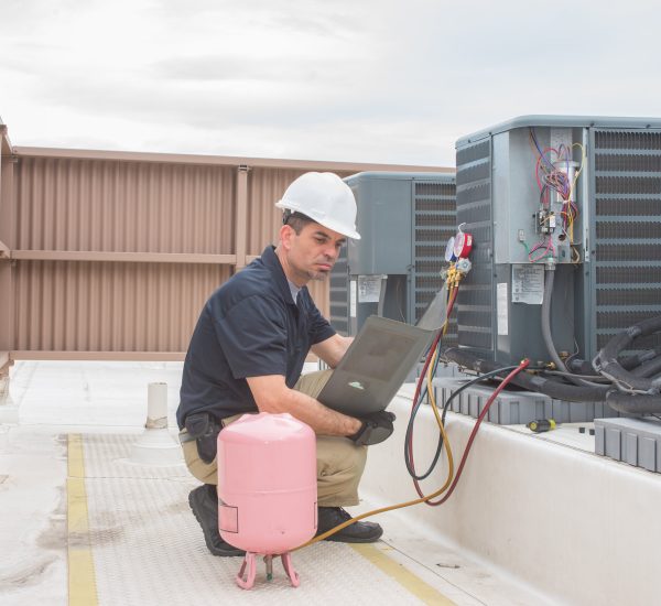 Technician looking at a panel off a condensing unit.